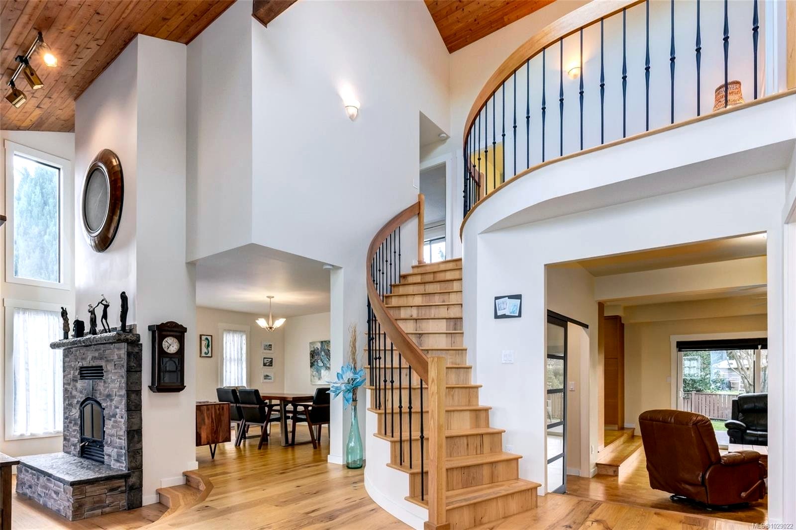 Complete transformation of the main entry featuring refinished hardwood flooring, vaulted ceilings, and a modernized curved staircase with custom railings.