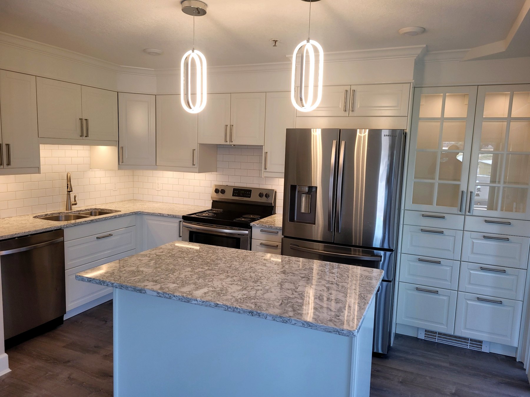 Fully renovated IKEA kitchen featuring custom cabinetry, expanded storage, quartz-style countertops, subway tile backsplash, modern lighting, and a bright open layout.