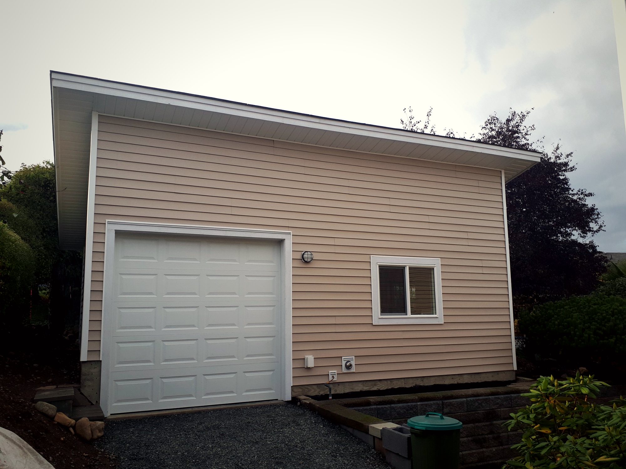 Completed detached garage exterior featuring durable low-maintenance siding, oversized roof overhangs, and integrated site drainage.