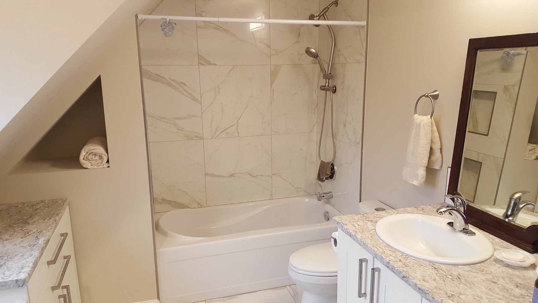 Full bathroom renovation with a new tub/shower area, tiled surround, vanity, fixtures, and updated finishes.